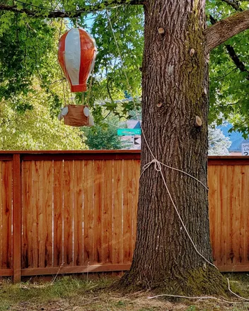A striped hot air balloon hanging from a tree in a back garden