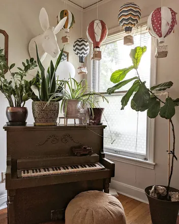 A living room with the donkey head on the wall and hot air balloons over the piano