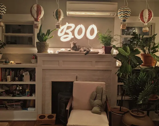 A glowing BOO sign over a fireplace, with hot air balloons hung from the ceiling