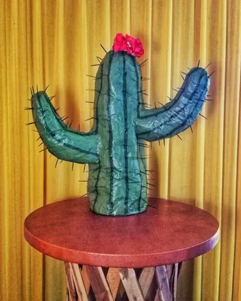 A green cactus piñata with a pink flower on top