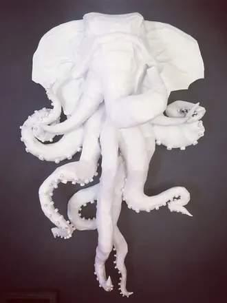 A white elephant with octopus tentacles, mounted on a dark wall