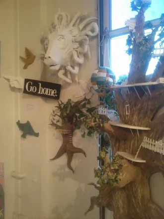 A white lion's head on a wall among pointing hands and a “Go home” sign