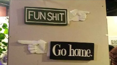 Two signs, “FUN SHIT” and “Go home.”, each with a white pointing hand