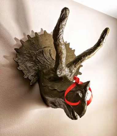 A triceratops head with a red bow