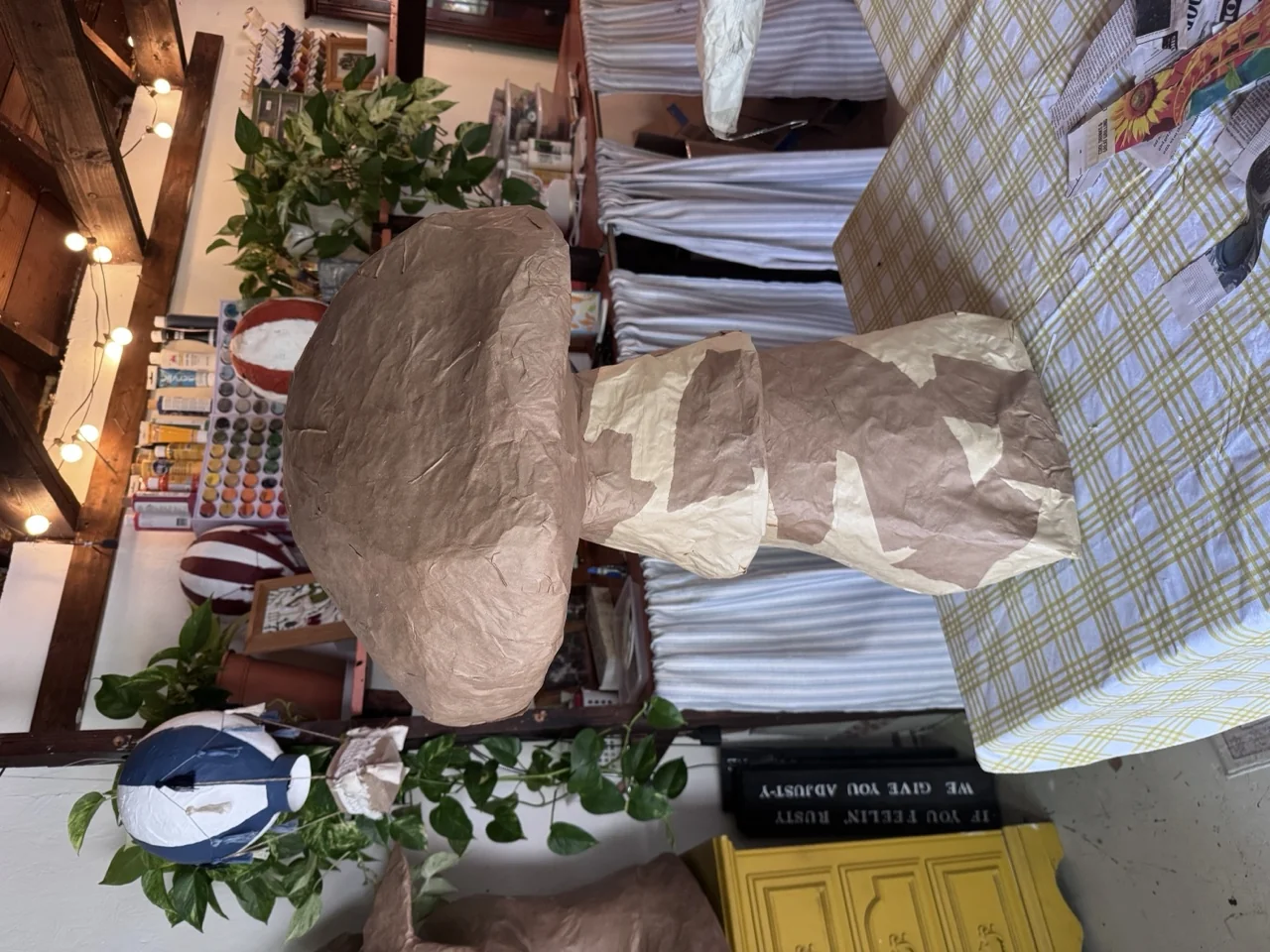 Paper mâché mushrooms — one waist-high, a shelf of spotted ones, and two small ones on string
