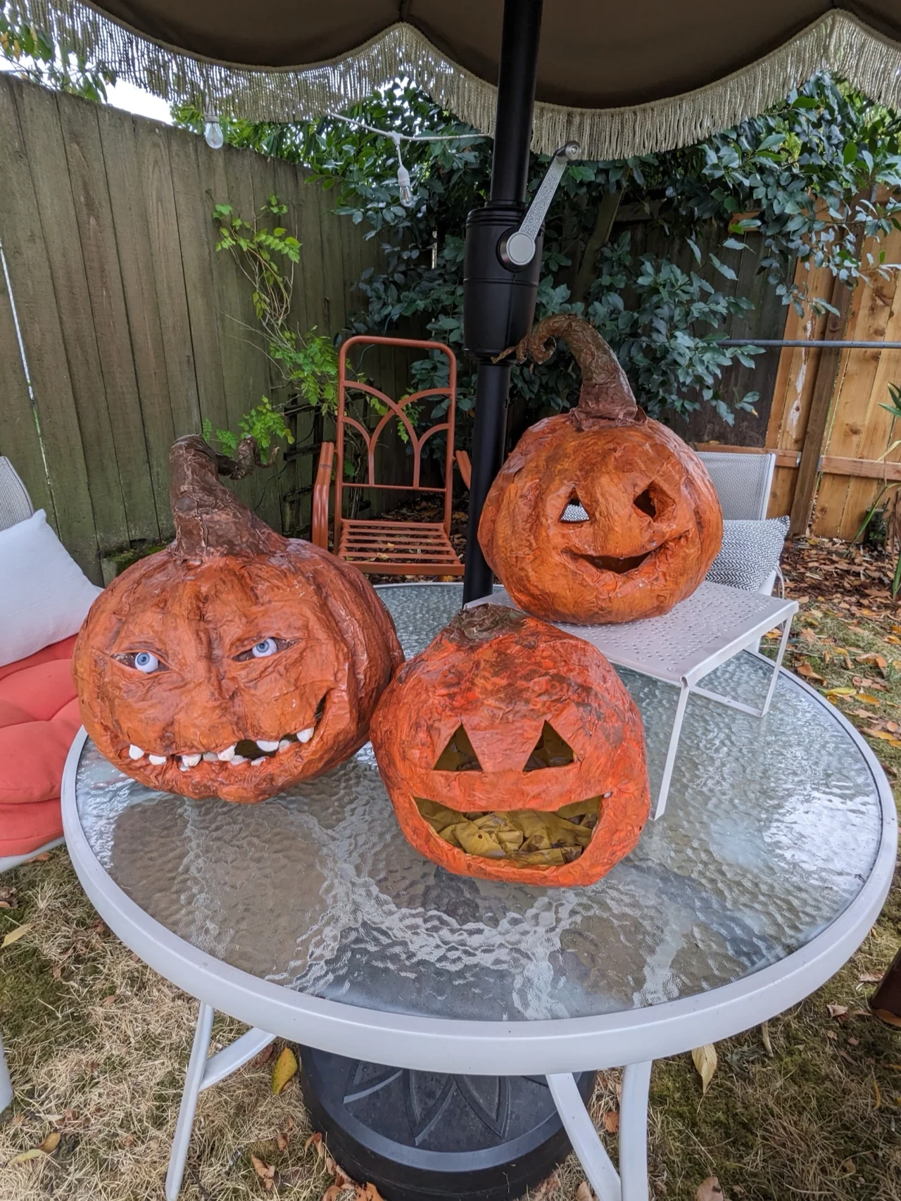 Three paper mâché jack-o-lanterns on a garden table